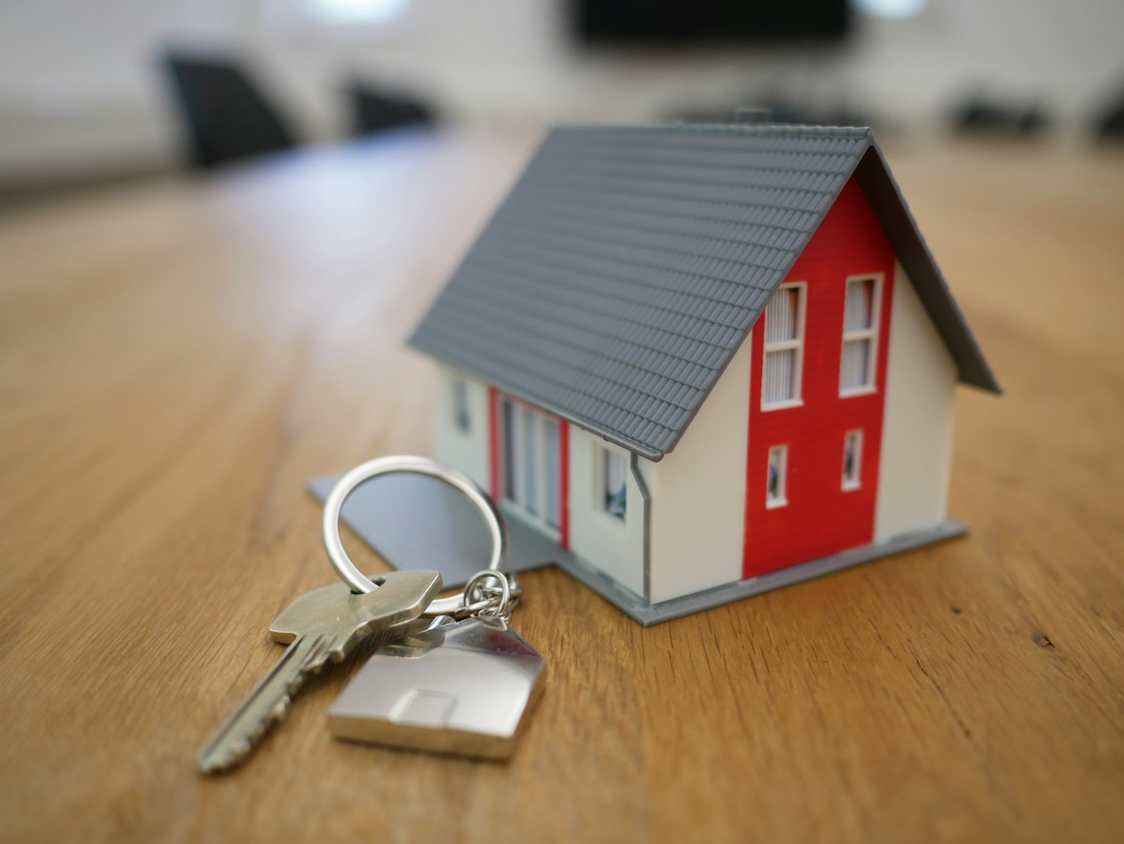 House keys beside a miniature home on a table
